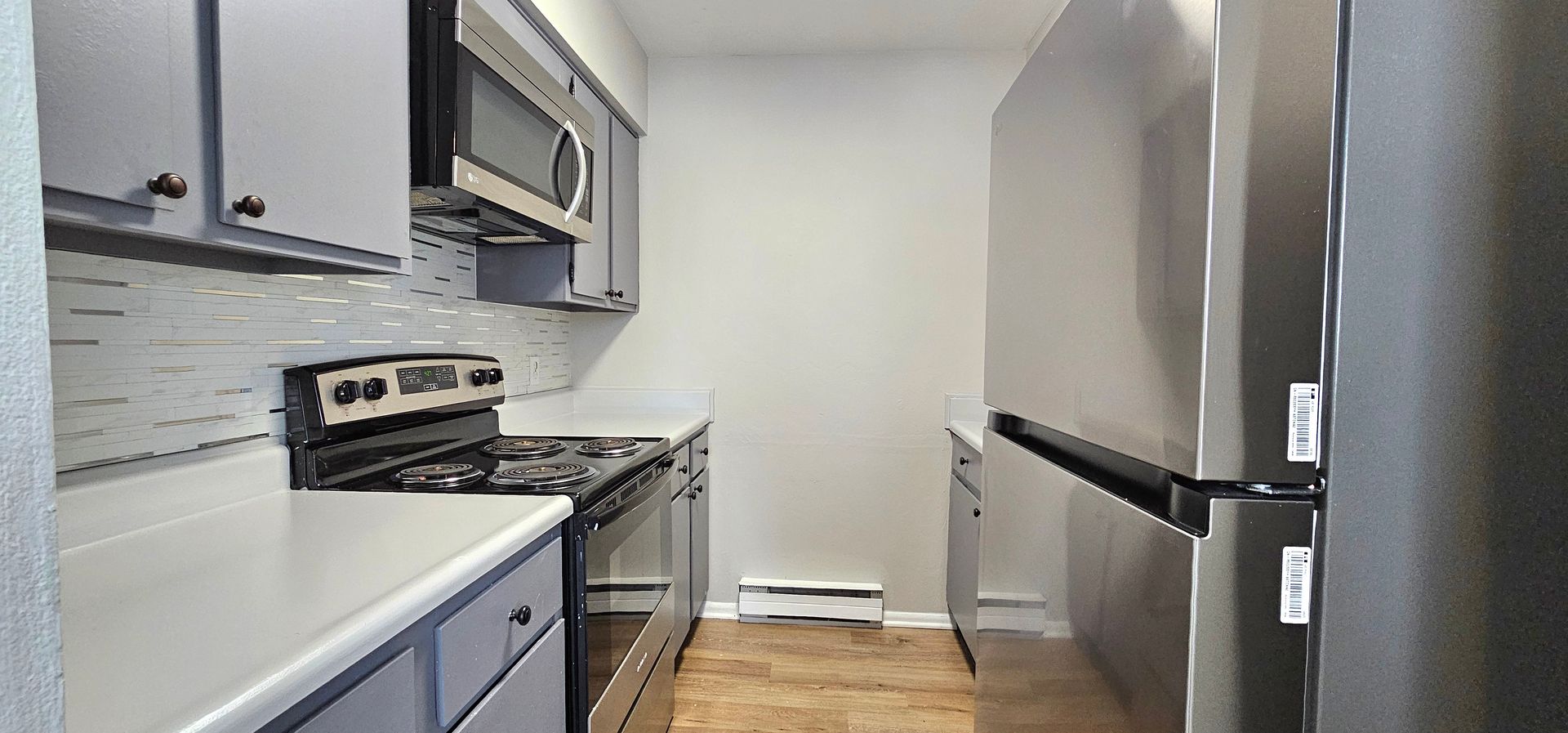Updated kitchen with stainless appliances, tile backsplash and wood-look floor