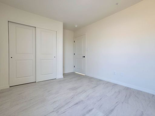 Unit 1 bedroom with closet and entry doors.