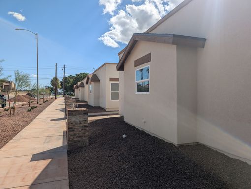 Unit 3 exterior beside a sidewalk and gravel beds.