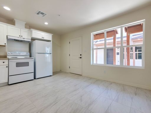 Unit 3 living space and kitchen beside a wide window.