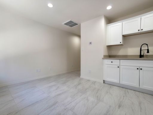 Unit 3 living space beside white kitchen cabinets.